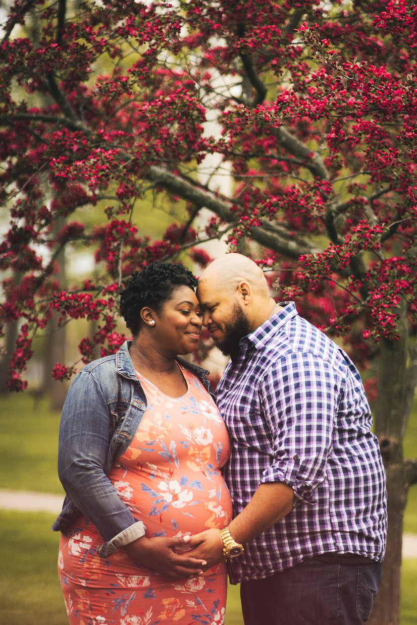 Pregnant black woman caressing husband near tree